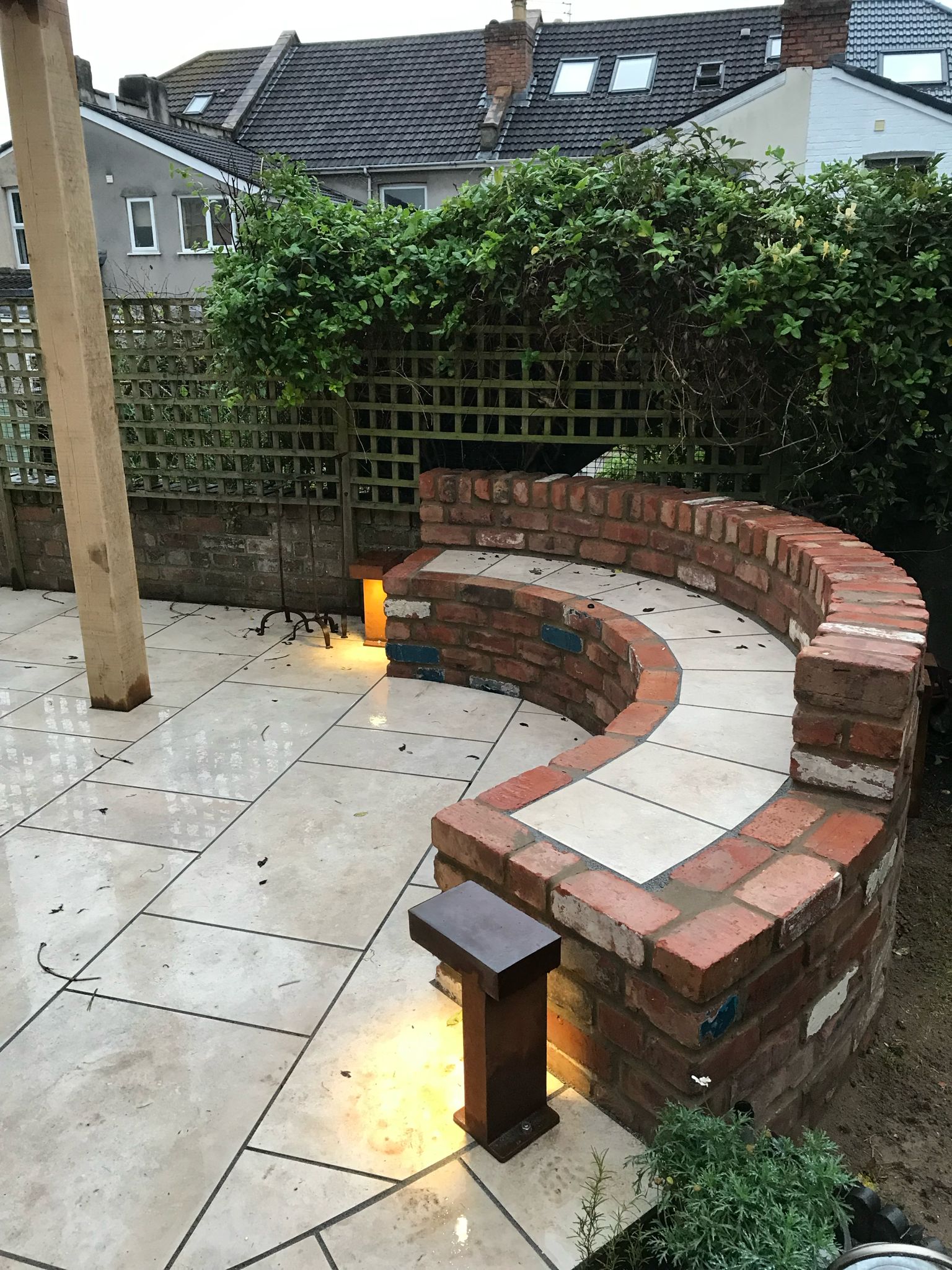 Curved brick seating wall with bollard lights on patio