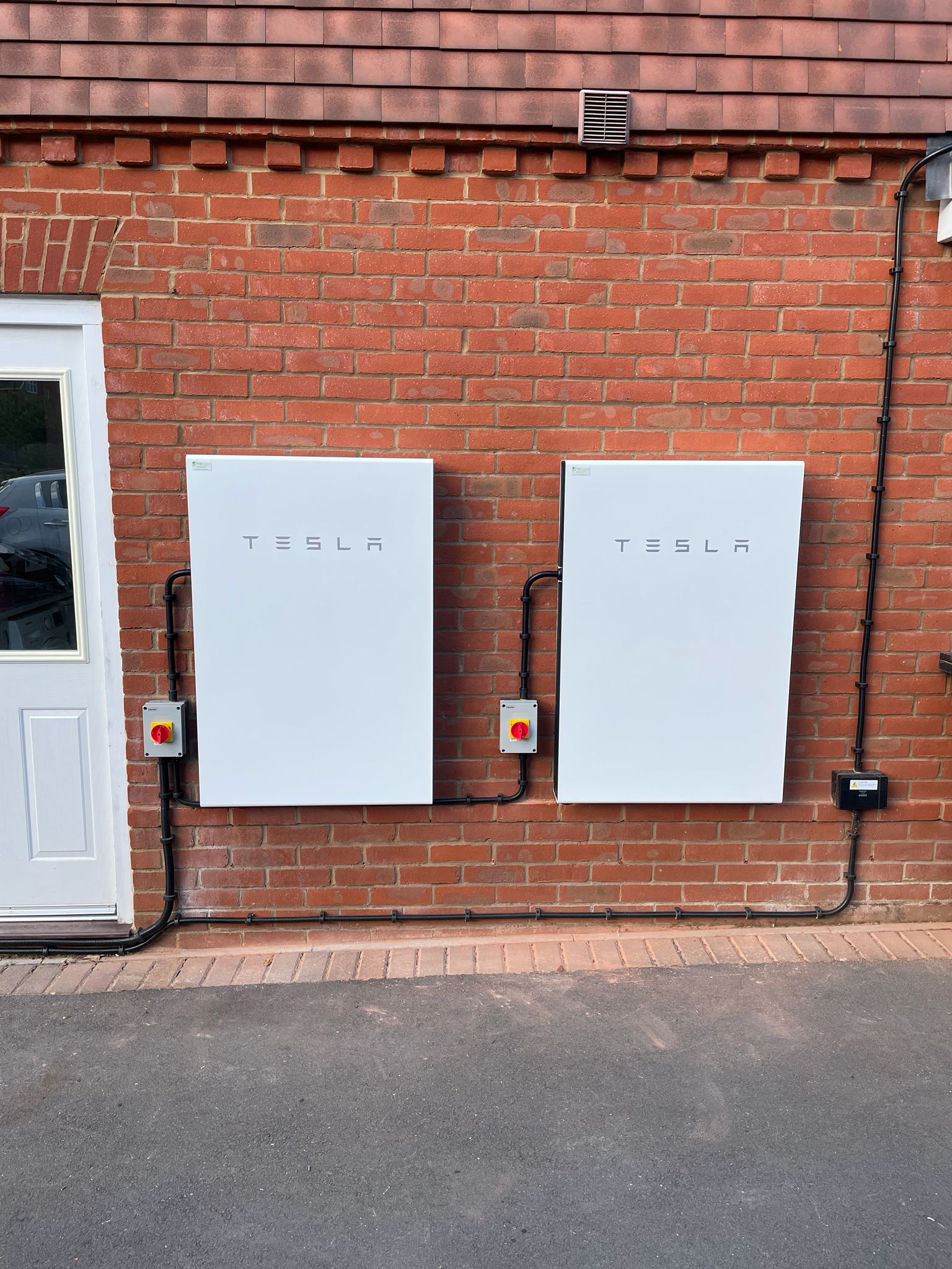 Dual Tesla Powerwall batteries mounted on brick wall