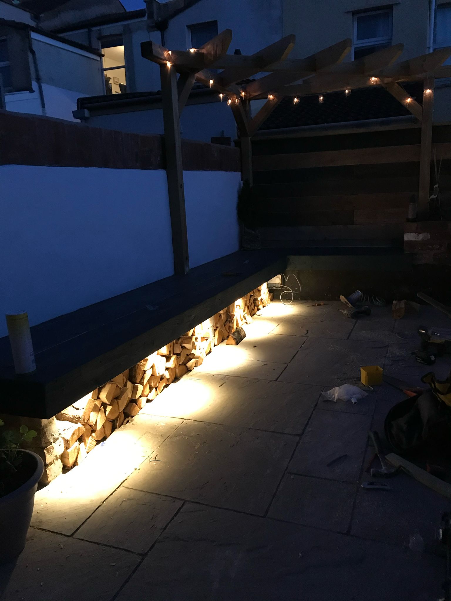 Patio with pergola festoon lights and illuminated log store