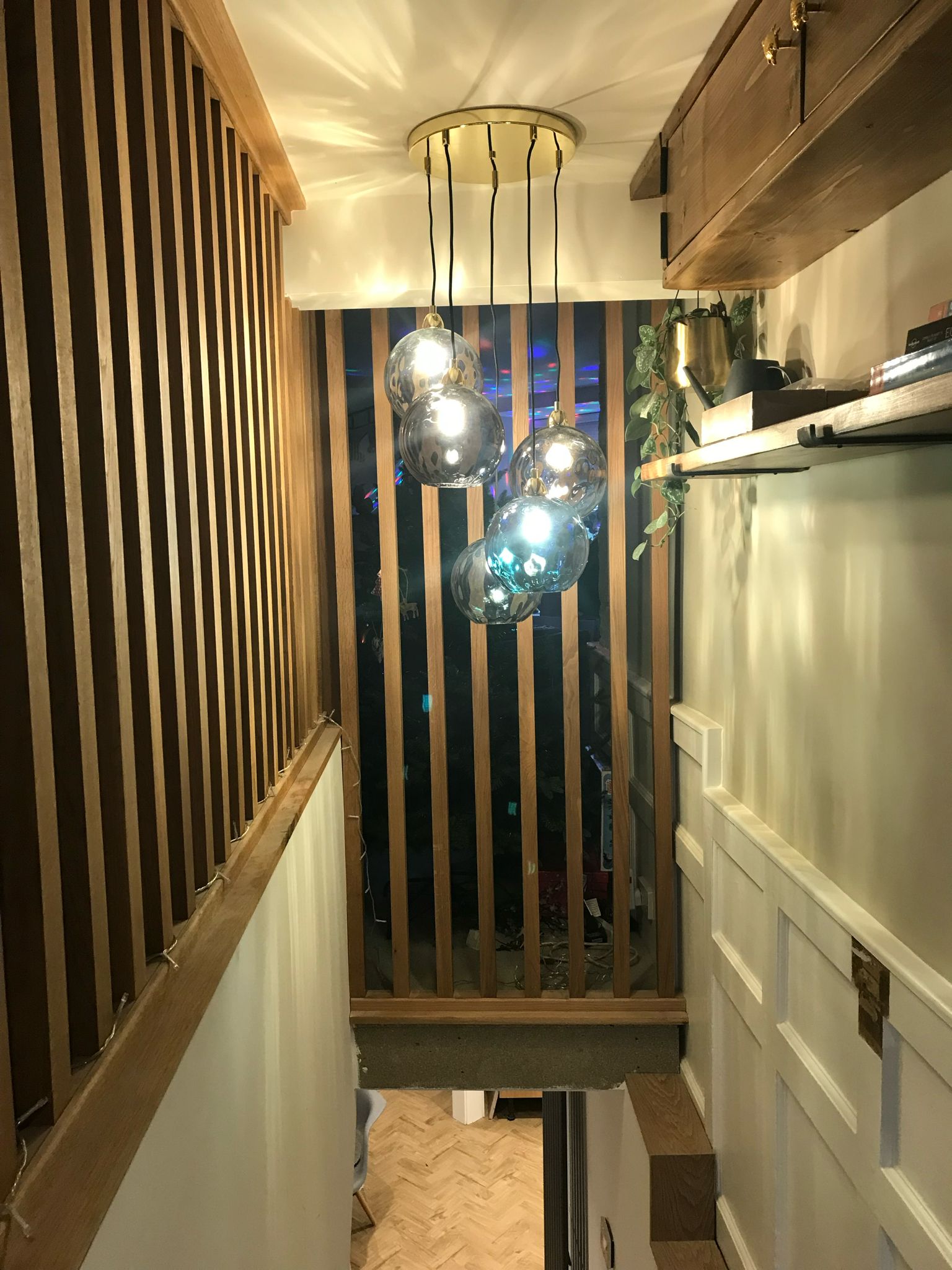 Stairwell glass pendant lights with timber slat feature wall