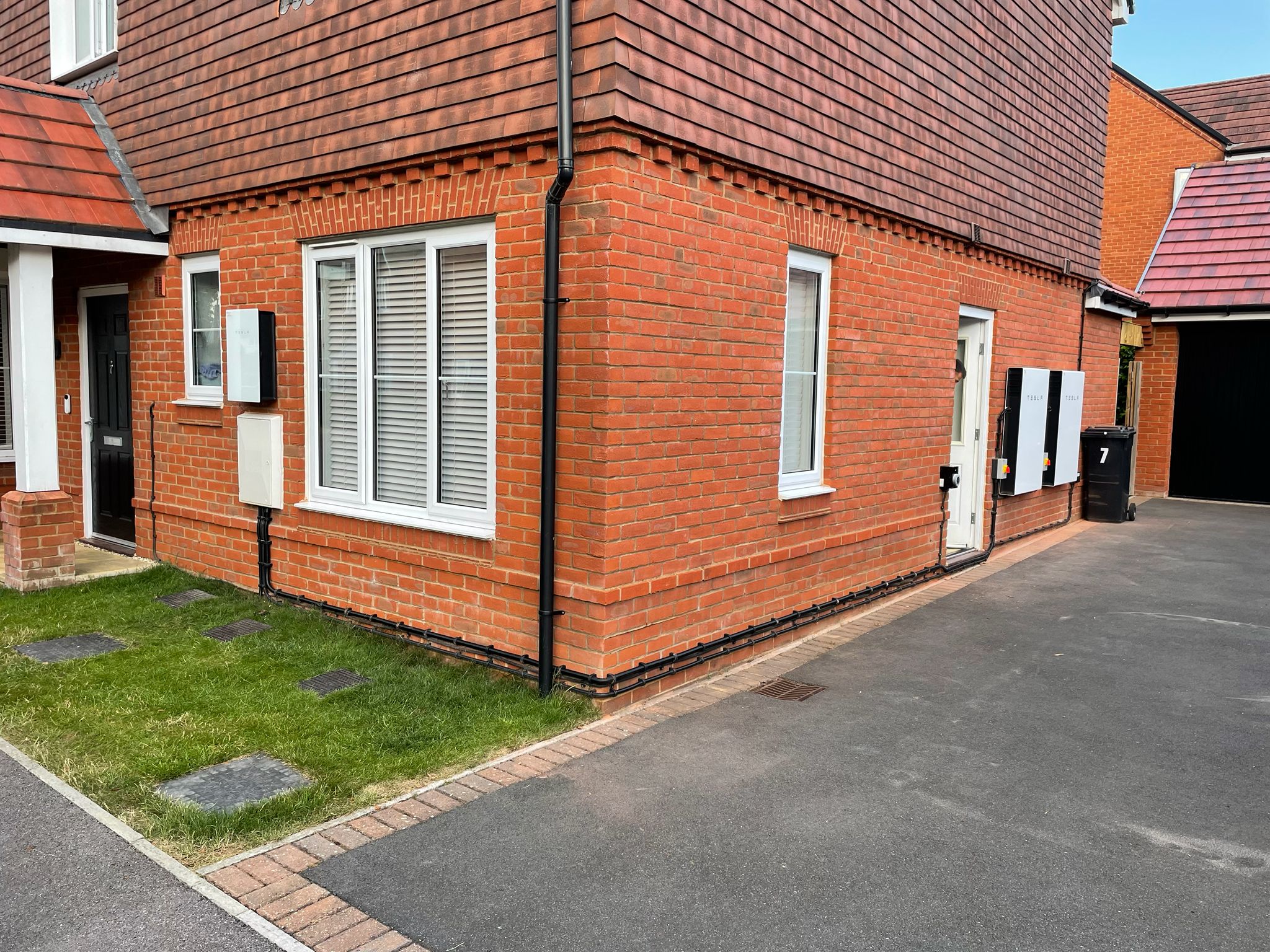 House exterior with dual Tesla Powerwalls and cable routing