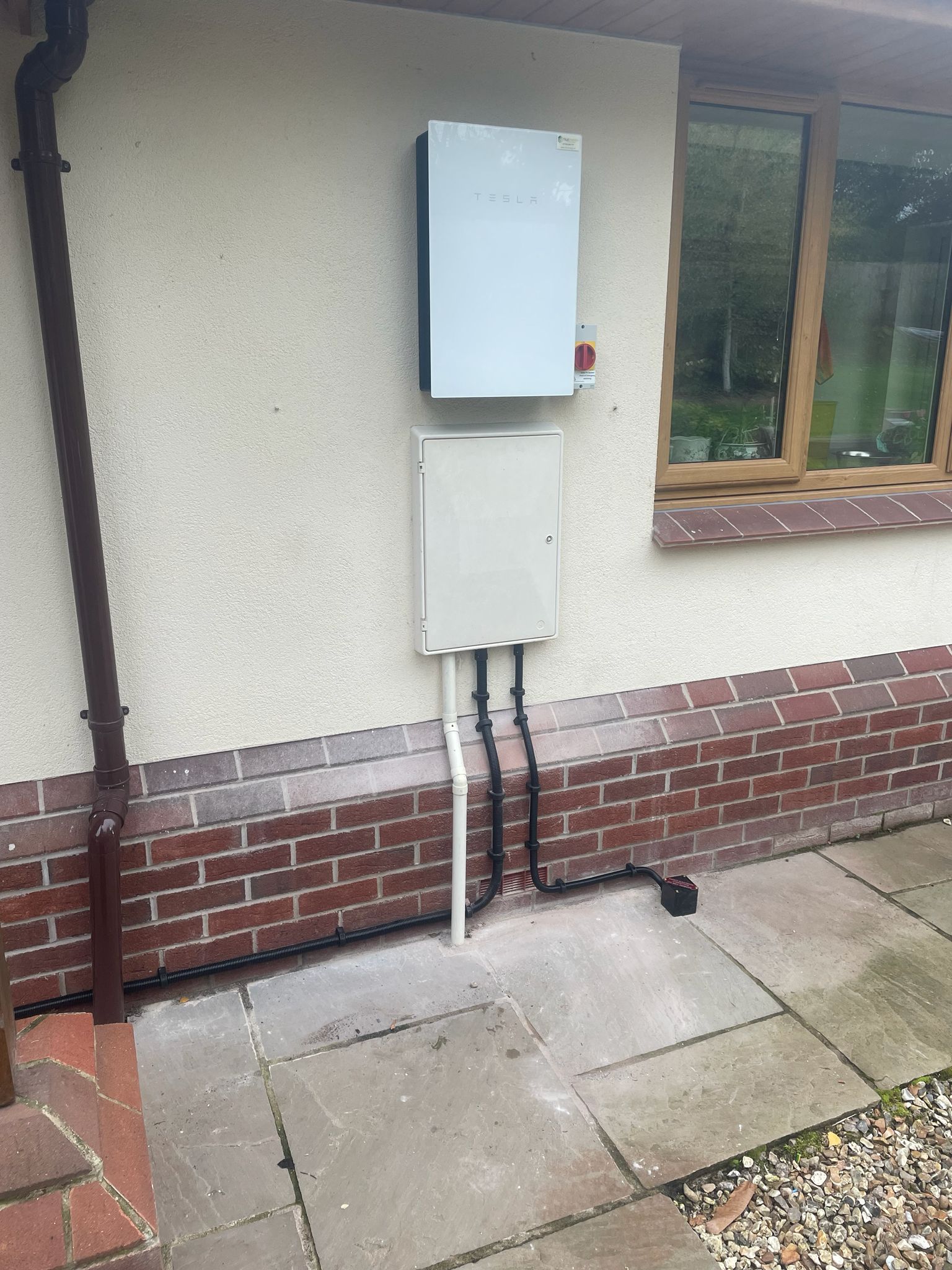 Tesla Powerwall with distribution board on rendered wall