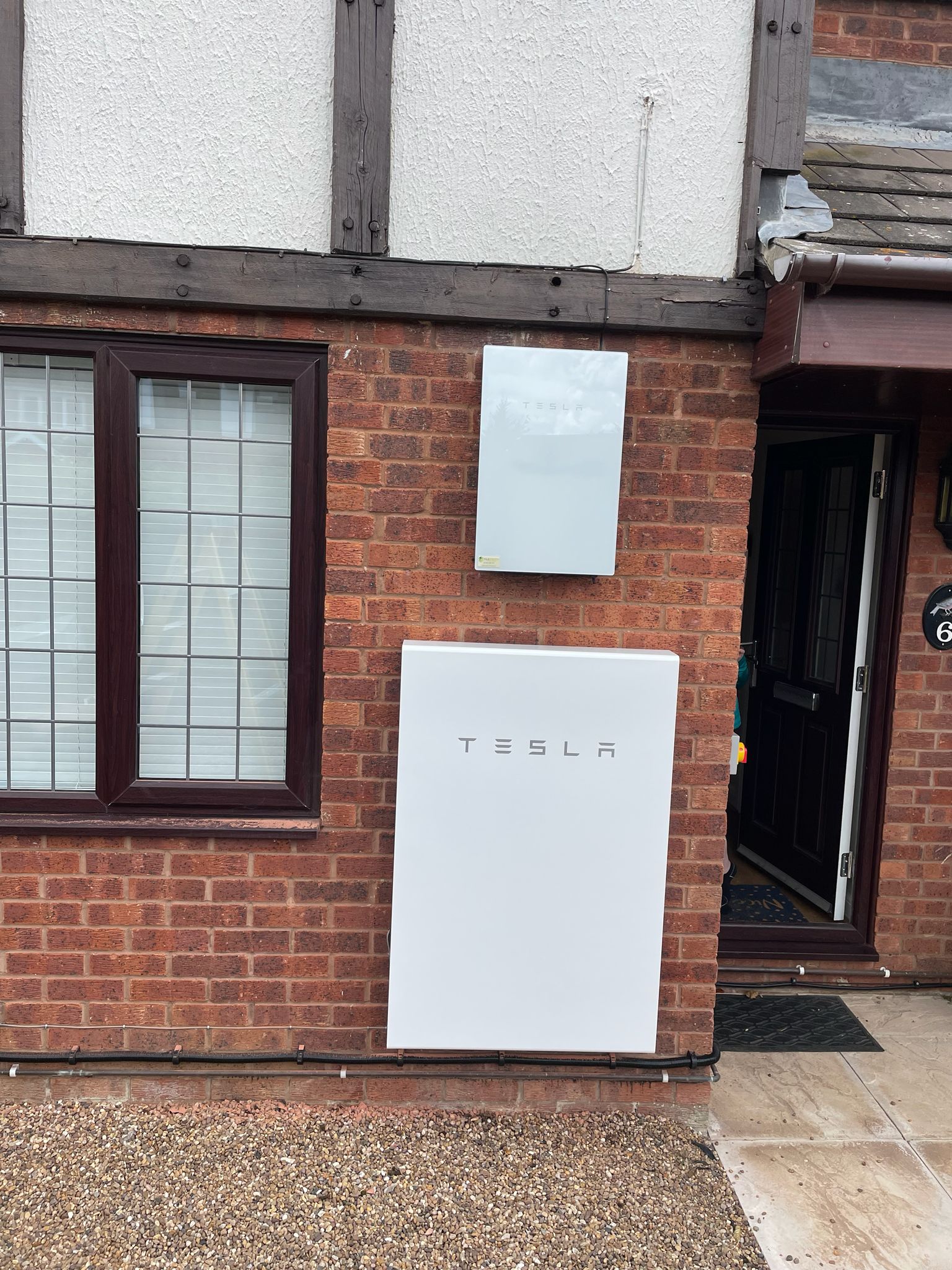 Tesla Powerwall and Gateway on Tudor-style brick house